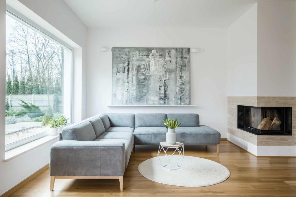 Modern living room with gray sectional sofa and large window with natural light