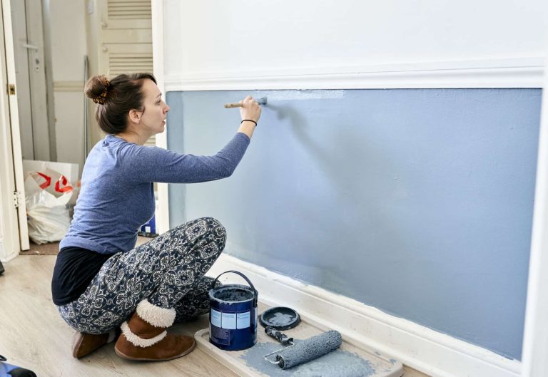 Woman painting a wall blue in a home interior renovation project